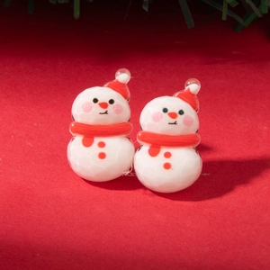 Macro shot of festive snowman earrings with red hat and scarf on red background