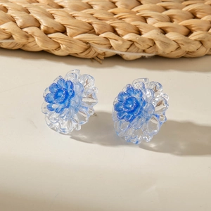 Detail of floral earrings featuring layered blue glitter petals and resin texture