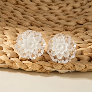 Macro detail of translucent frosted flower stud earrings with shimmering silver glitter center