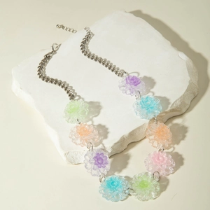 Detail of colorful resin flower necklace with silver chain on textured stone