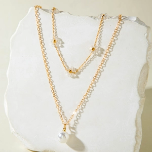 Dettaglio della collana multistrato dorata con perle finte e ciondoli a fiore