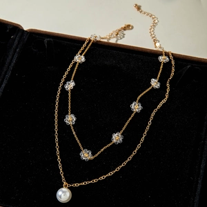 Dettaglio collana dorata a strati con perla e fiori di cristallo su velluto nero