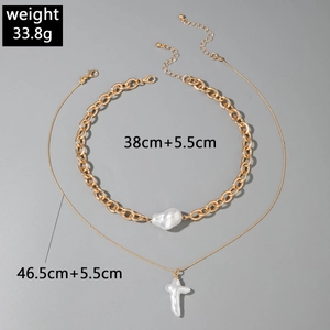 Détail du collier multirang doré avec perle baroque et pendentif croix blanche élégant