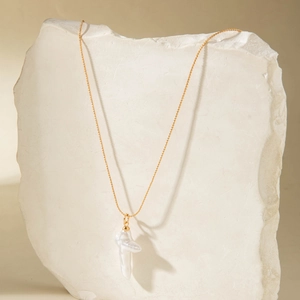 Gros plan du collier Y doré avec perle baroque élégante sur un socle en pierre