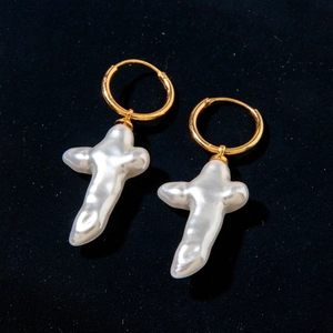Vue détaillée de boucles d'oreilles en perle baroque en forme de croix sur velours
