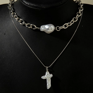 Détail d'un collier à deux rangs avec perles baroques et pendentif croix argenté