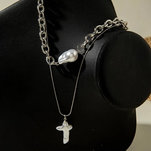 Détail d'un collier argenté double épaisseur avec perles baroques et croix