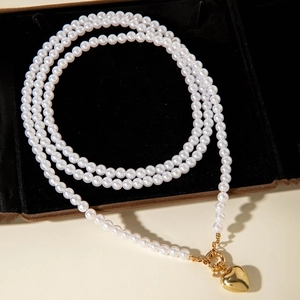 Collar de perlas multicapa con colgante de corazón dorado y cierre OT sobre terciopelo