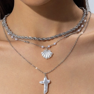 Gros plan du collier triple rang argenté avec pendentifs coquillage et croix en perle