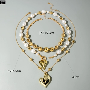 Detalle de colgantes de corazón dorados y collares de perlas con medidas de tamaño