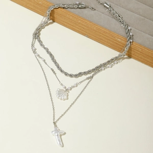 Détail du collier argenté multicouche avec pendentif en coquillage et une croix