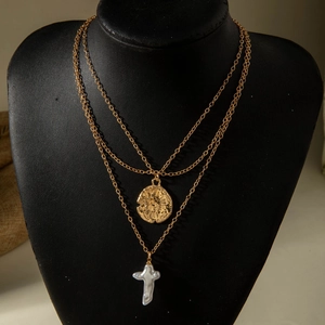 Détail du collier multi-rangs doré avec médaille martelée et croix en perle baroque