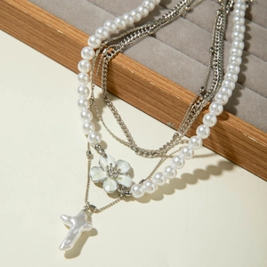 Détail d'un collier de perles multicouche avec breloque fleur et pendentif croix