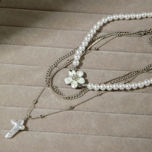 Détail du collier argenté multicouche avec fleur en cristal et croix en perle baroque