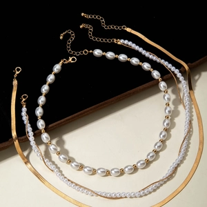 Vista detallada del collar de varias capas con perlas blancas y cadena de serpiente dorada