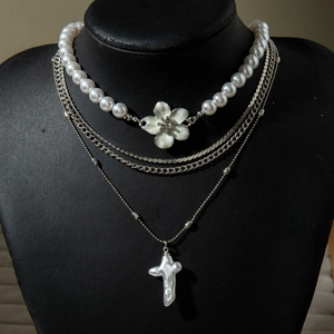 Détail d'un collier de perles multicouches avec chaînes argentées et pendentif croix