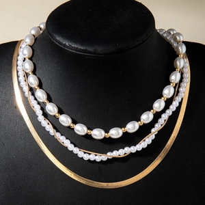 Detalle del collar de varias capas con perlas barrocas y cadenas metálicas doradas finas