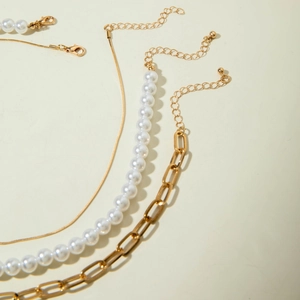Detalle del conjunto de collares con cadena de serpiente dorada, perlas y eslabones de clip