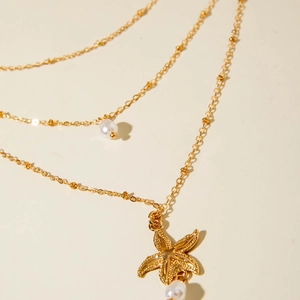 Close-up of gold layered starfish necklace with faux pearls and textured starfish charm