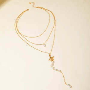 Detailed view of triple-layered gold star necklace with pearls and starfish charms