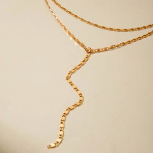 Macro view of gold Y-shaped tassel necklace featuring textured oval metal chain links