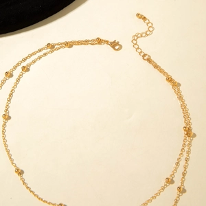 Detail view of golden double-layer necklace with lobster clasp and adjustable extension chain