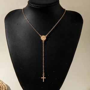 Detail of a gold-plated Y-necklace with religious medal and cross pendant on a mannequin