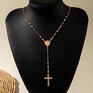 Close-up of golden rosary y-necklace featuring a religious medal and crucifix pendant