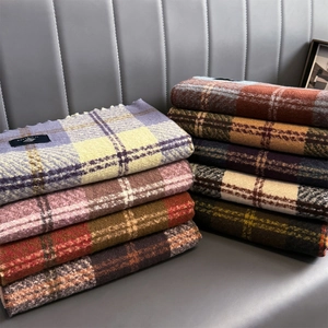 Close-up of thick plaid cashmere scarves showing colorful woven texture and fringe details