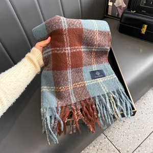 Detail of thick blue and red plaid scarf featuring soft fringe and brand label