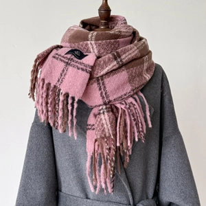 Close-up of thick plaid scarf in pink and brown with long decorative fringe detail