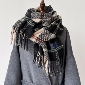 Detail of thick Christmas plaid scarf with long tassels and soft cashmere texture