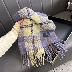 Close-up of thick winter scarf featuring a purple plaid pattern and soft fringe tassels