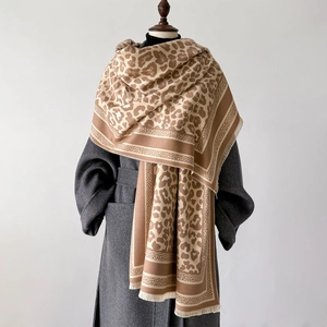 Detail of soft leopard print scarf with tassel edge on a grey wool coat for winter