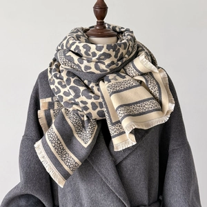 Close-up of leopard print scarf with tassels over a grey coat on a mannequin stand
