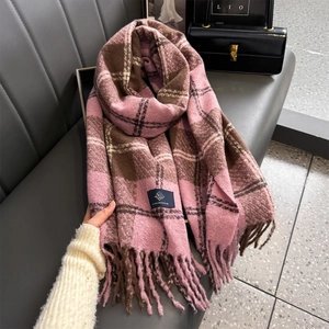 Pink and brown plaid cashmere scarf with long tassels displayed on a grey leather bench