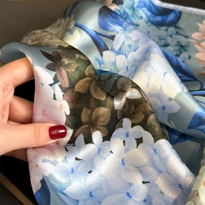 Premium mulberry silk scarf with blue floral patterns and smooth satin texture for women