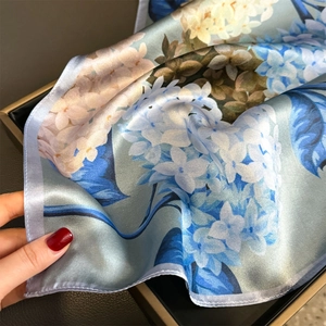 Elegant mulberry silk scarf with blue floral prints and satin texture in a gift box