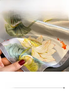 Detailed view of silk scarf edges featuring lotus print and fine hand-rolled stitching