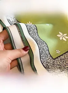 Macro detail of high-density overlock edge on a green silk scarf with floral pattern