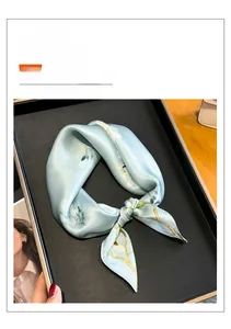 Gros plan d'un foulard carré en pure soie de mûrier à fleurs blanches sur fond bleu clair