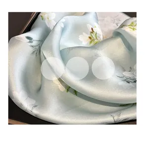 Détail du foulard en soie vert clair avec motif élégant de fleurs de magnolia blanc