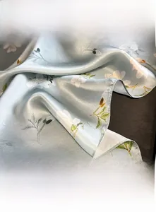 Détail d'un foulard en soie bleue montrant les coutures fines et l'imprimé magnolia
