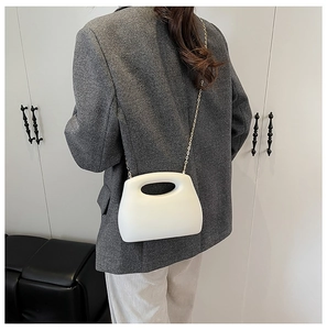 Back view of model wearing a white acrylic box bag with gold chain and handle