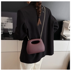 Deep purple acrylic box bag with gold chain strap shown in a modern lifestyle setting