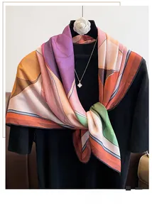 Detail of silk-like square scarf with geometric print and camellia brooch styling