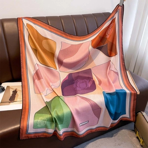 Elegant large square silk scarf with geometric rose floral prints on a leather sofa