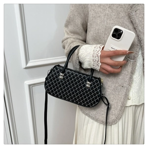 Bolso acolchado negro con tachuelas llevado por una modelo en un ambiente minimalista