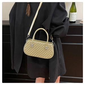 Detalle de bolso acolchado dorado con tachuelas y esferas plateadas sobre un abrigo negro