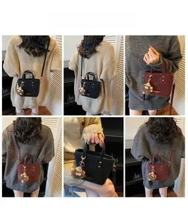Detail view of mini bucket bag in black and burgundy with plush lion charm